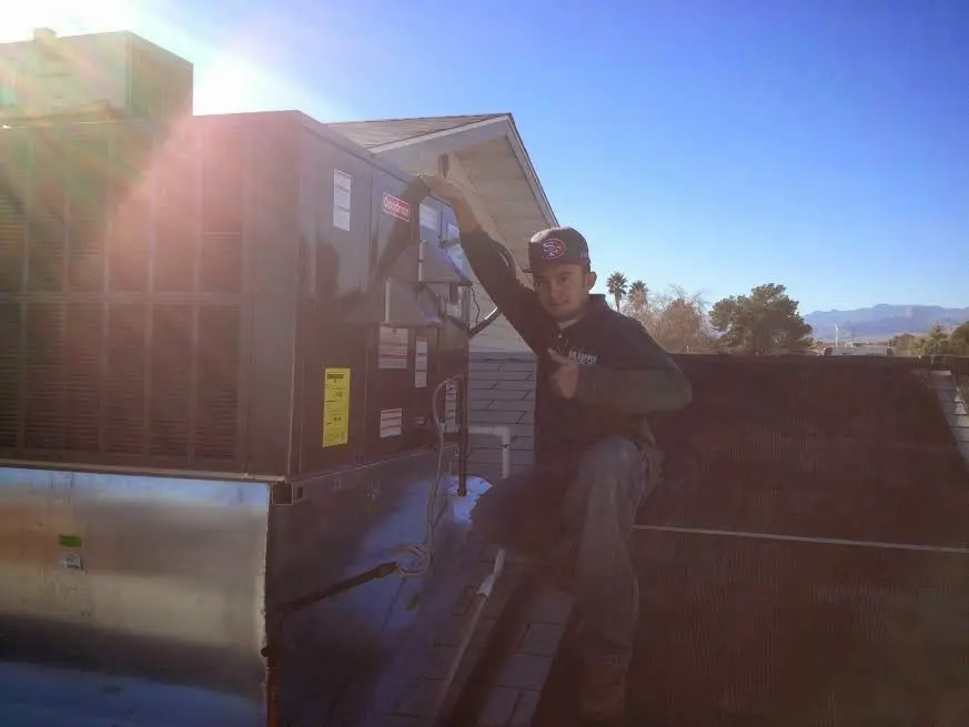 HVAC technician performing Air Duct Cleaning on a rooftop unit in Asheboro